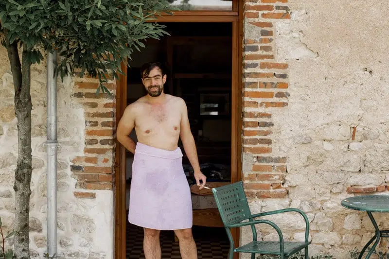 Homme, se tenant devant une porte d'entrée, torse nu avec une serviette