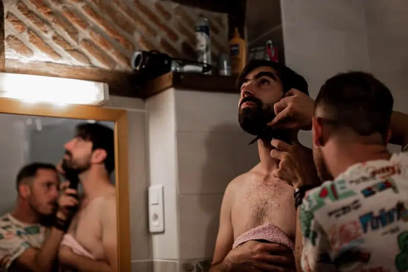Homme qui rase la barbe du Marié on voit leur reflet dans le miroir