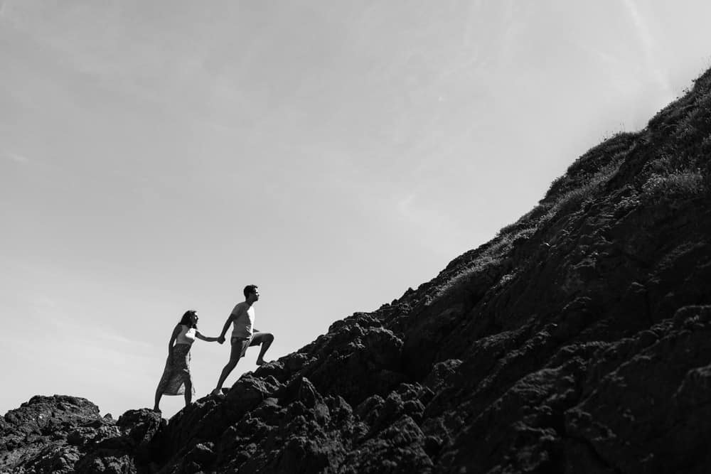 couple se tenant la main en montant une falaise
