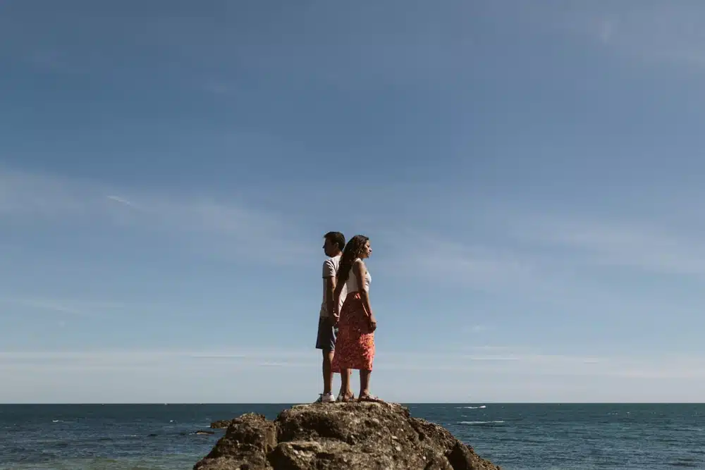 couple dos à dos face à la mer sur un rocher