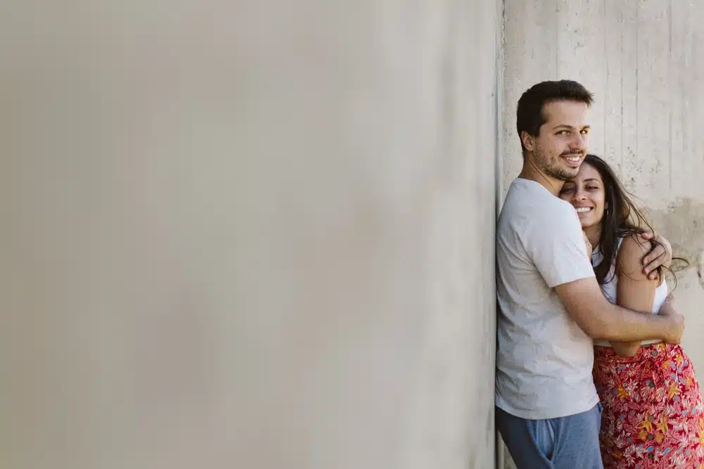 couple qui s'enlace appuyé à un mur