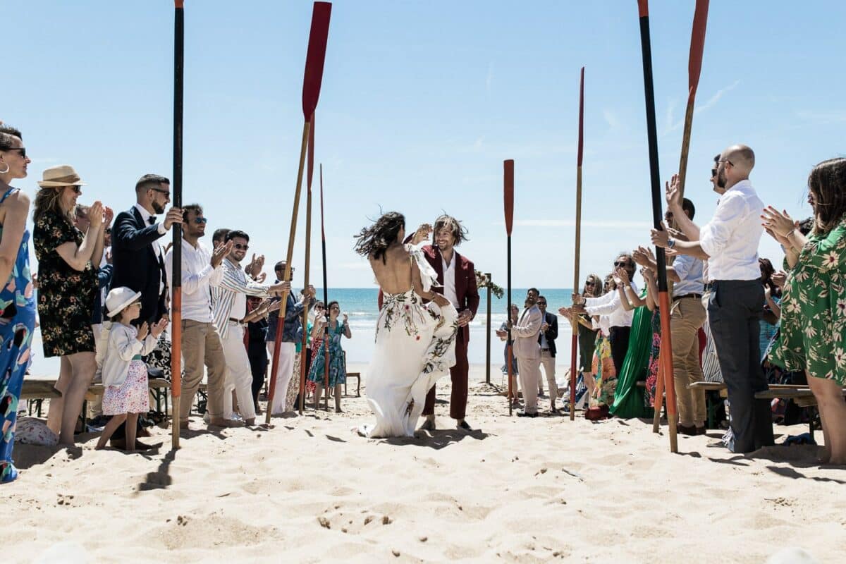 Garde d’honneur à la rame sur la plage, les mariés avancent en riant — mariage à Saint-Jean-de-Monts, Vendée