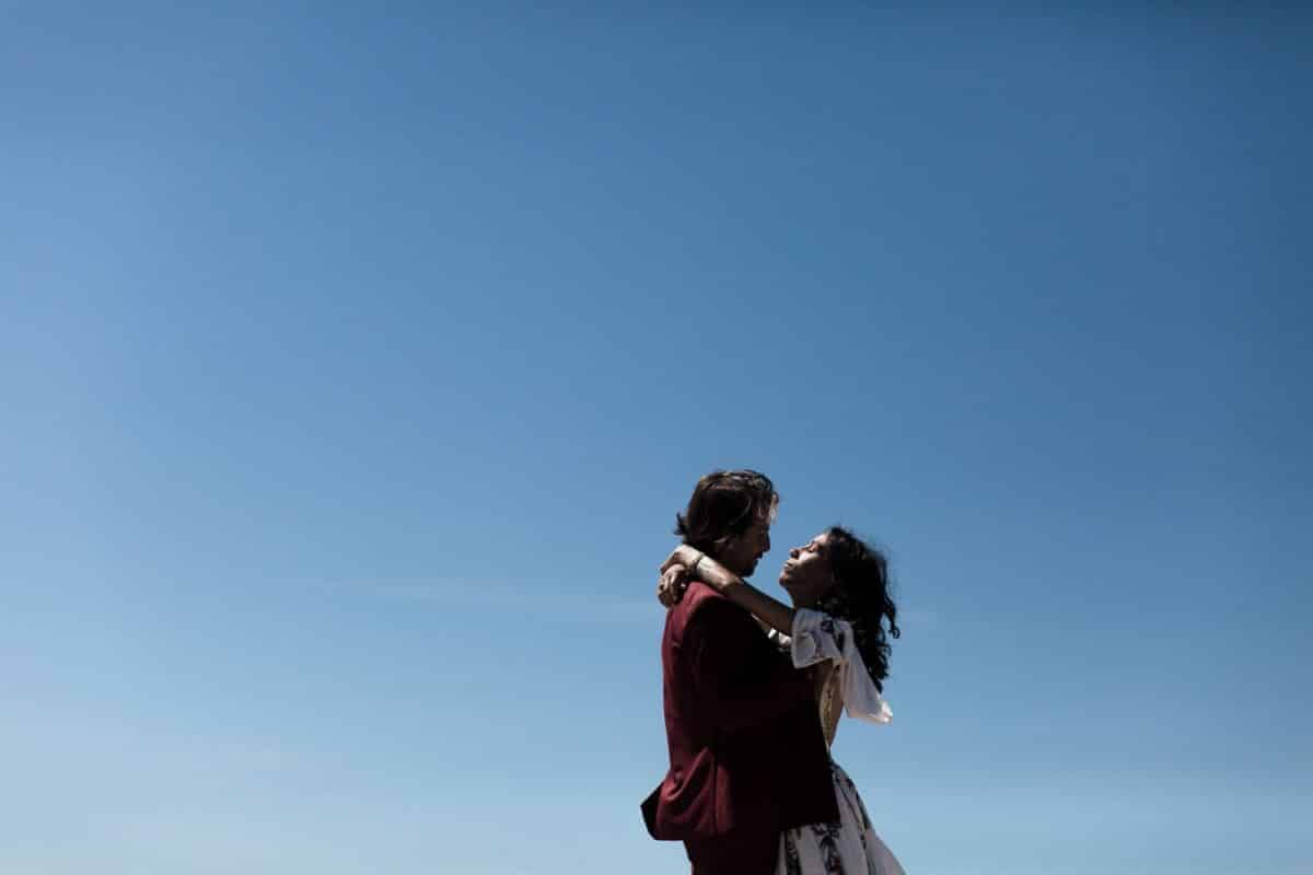Les mariés s’enlacent sous un ciel bleu immense — mariage sur la plage en Vendée.
