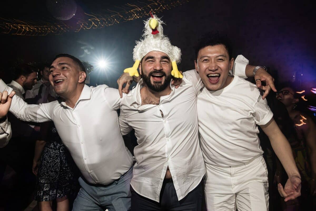 Soirée de mariage, amis bras dessus sur la piste, ambiance festive et débridée.