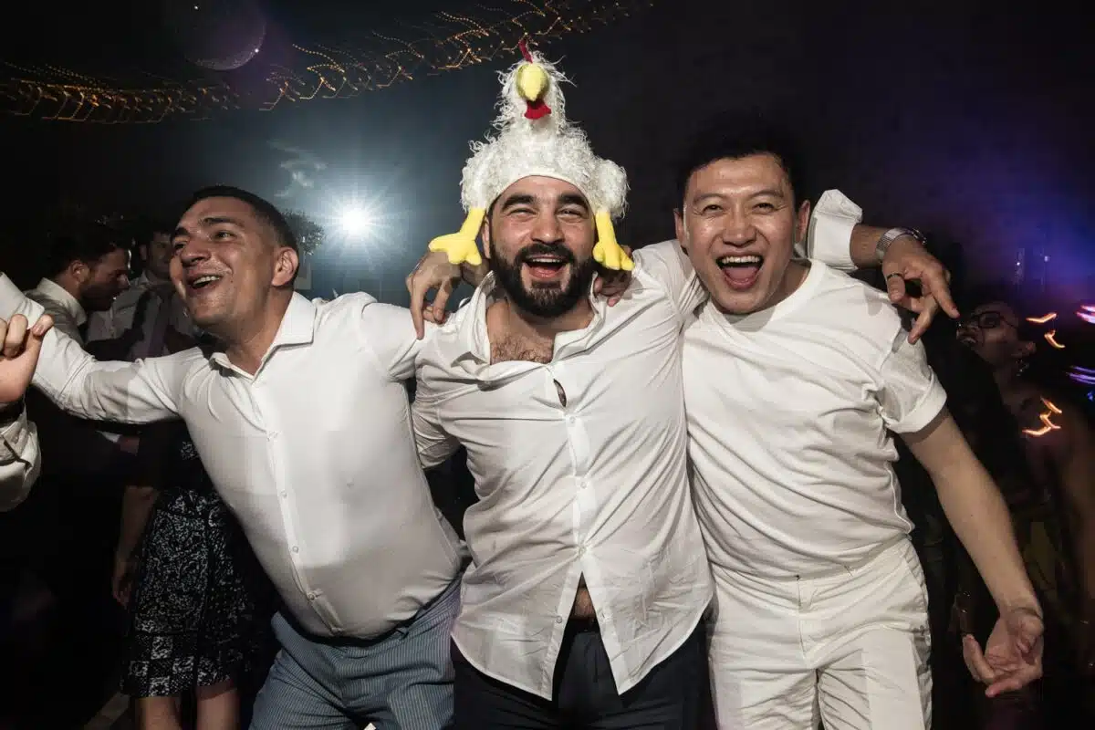 Soirée de mariage, amis bras dessus sur la piste, ambiance festive et débridée.