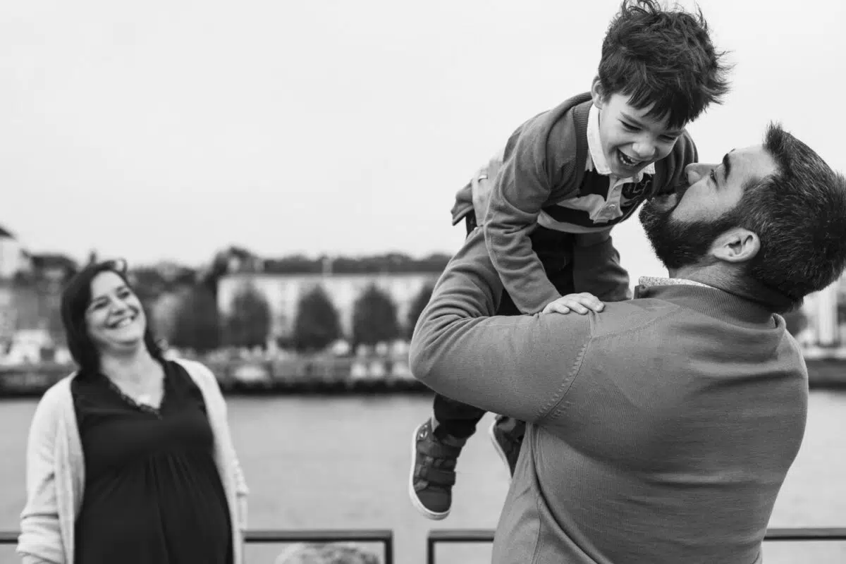 fils dans les bras de son père et mère en arrière plan