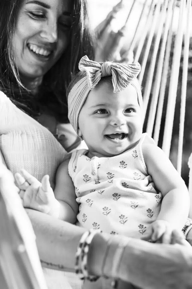 enfant qui sourit dans les bras de sa maman