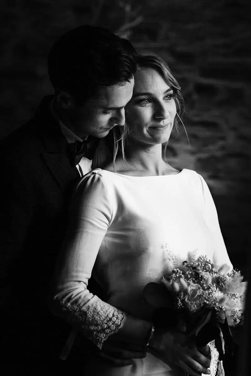 Portrait en noir et blanc d’un couple de mariés enlacés, moment d’émotion capturé par photographe de mariage.