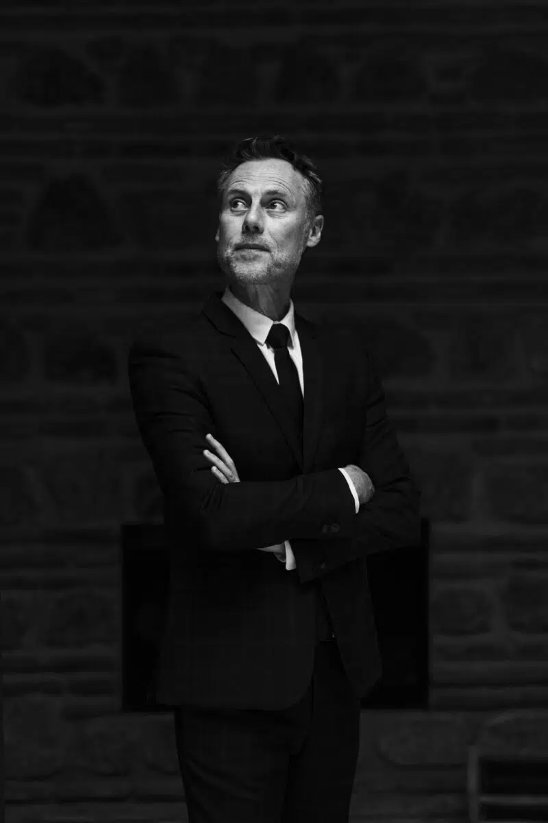 Portrait du marié en costume sombre, bras croisés, lumière douce — mariage dans la médina au Maroc.