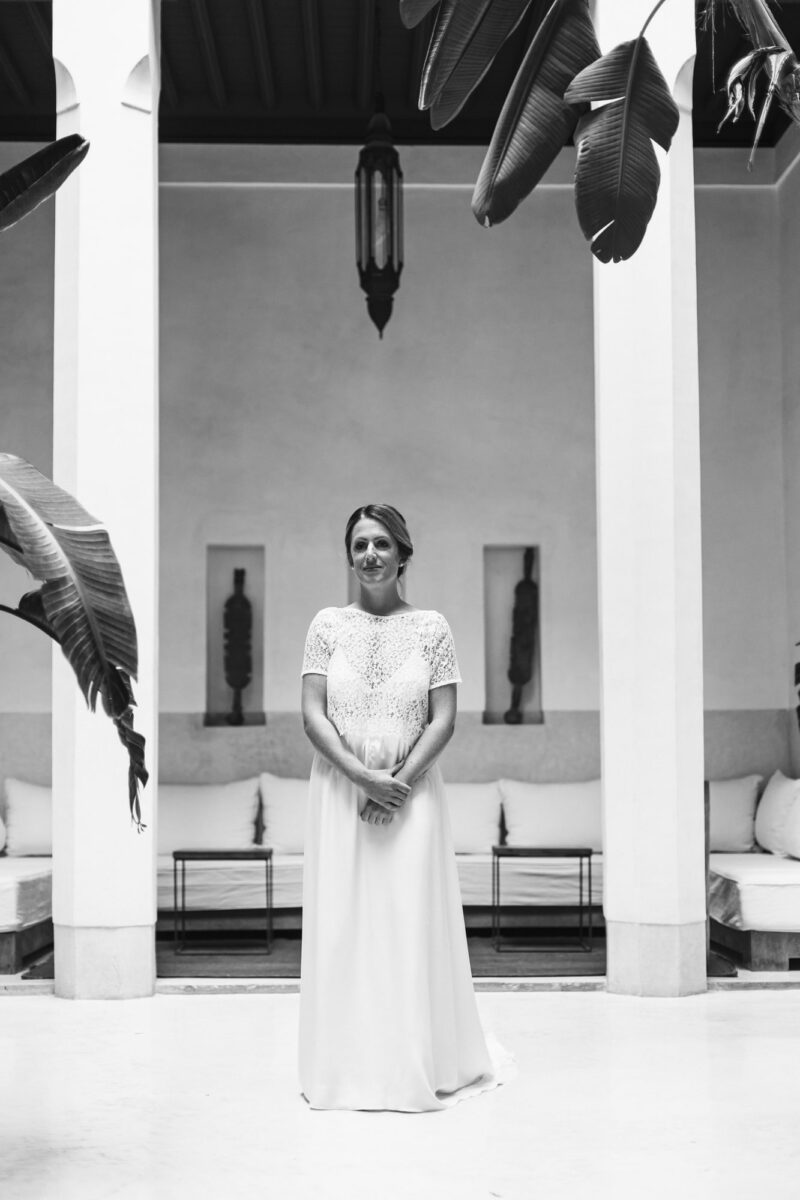 Portrait de la mariée dans le patio d’un riad, robe fluide et dentelle — mariage dans la médina au Maroc.