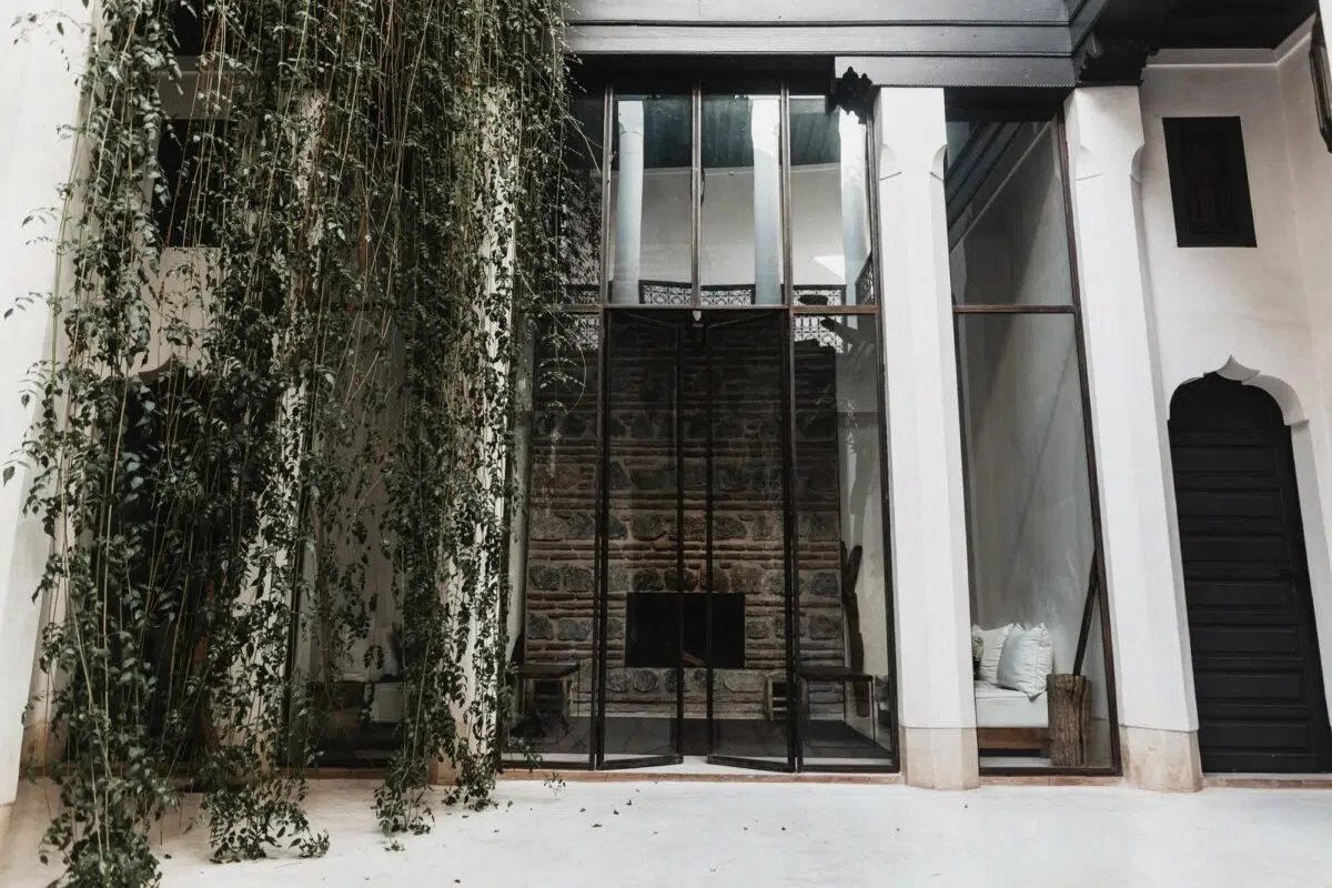 Patio d’un riad dans la médina, grande verrière sur mur de pierre et banquette — décor de mariage au Maroc.