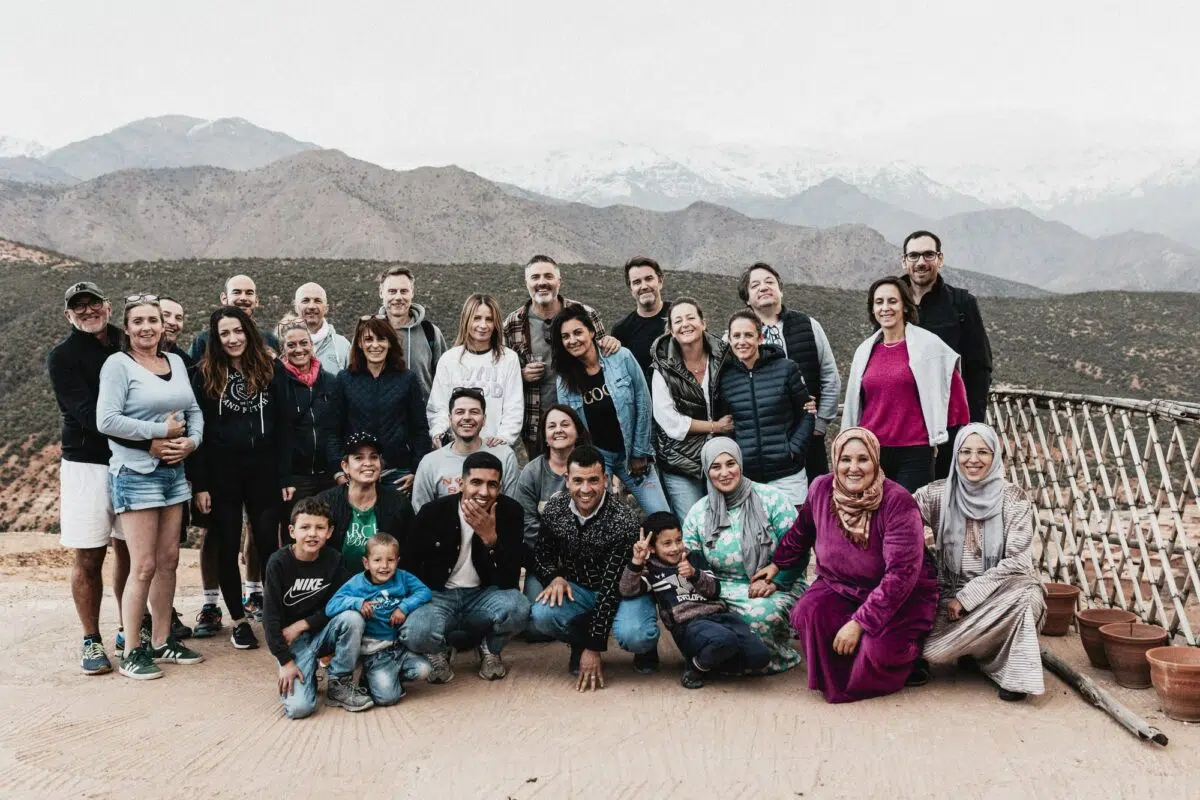 Photo de groupe des invités avec les montagnes de l’Atlas en arrière-plan – mariage au Maroc, ambiance conviviale.