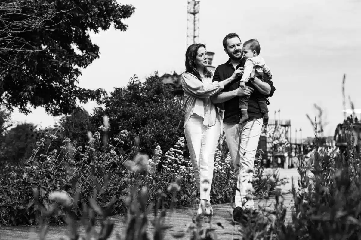 Couple avec enfant marchant parmi les massifs fleuris du Parc des Chantiers.