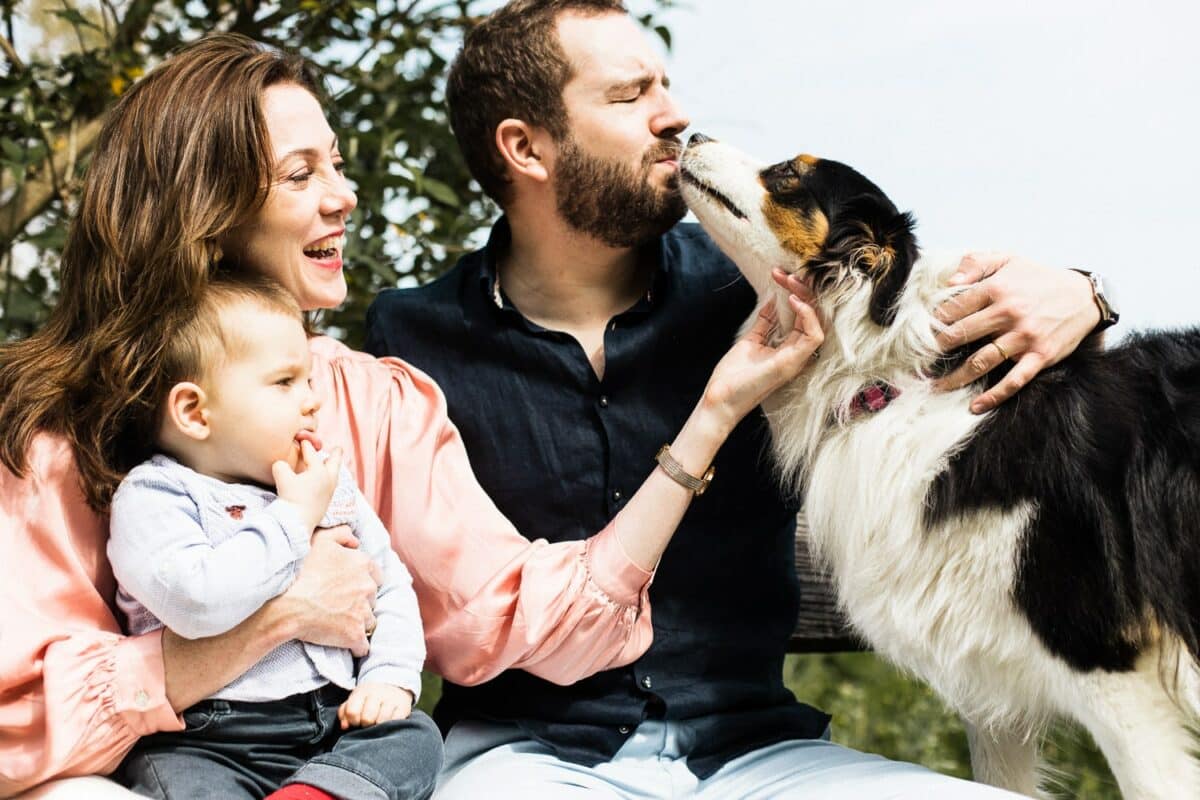 Portrait famille : le chien lèche le père, rires de la mère et de l’enfant.