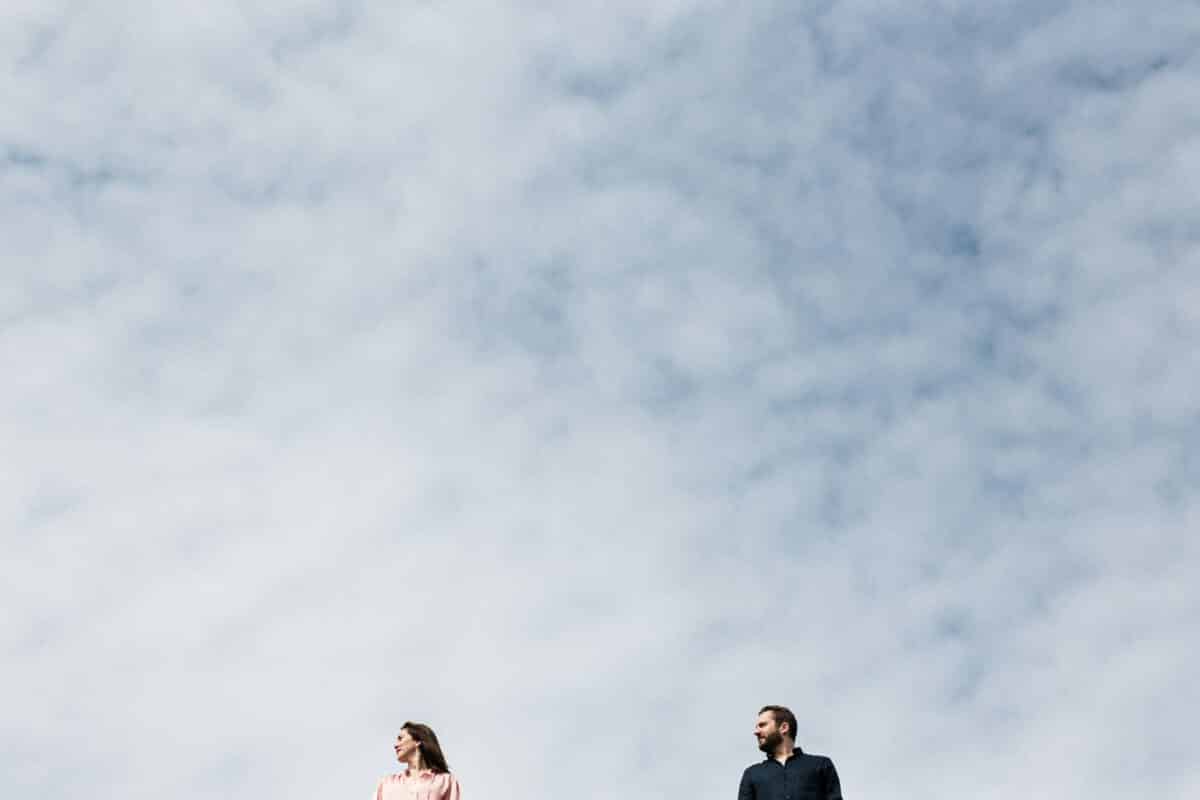 Couple cadré bas sous vaste ciel nuageux, ambiance minimaliste à Nantes.