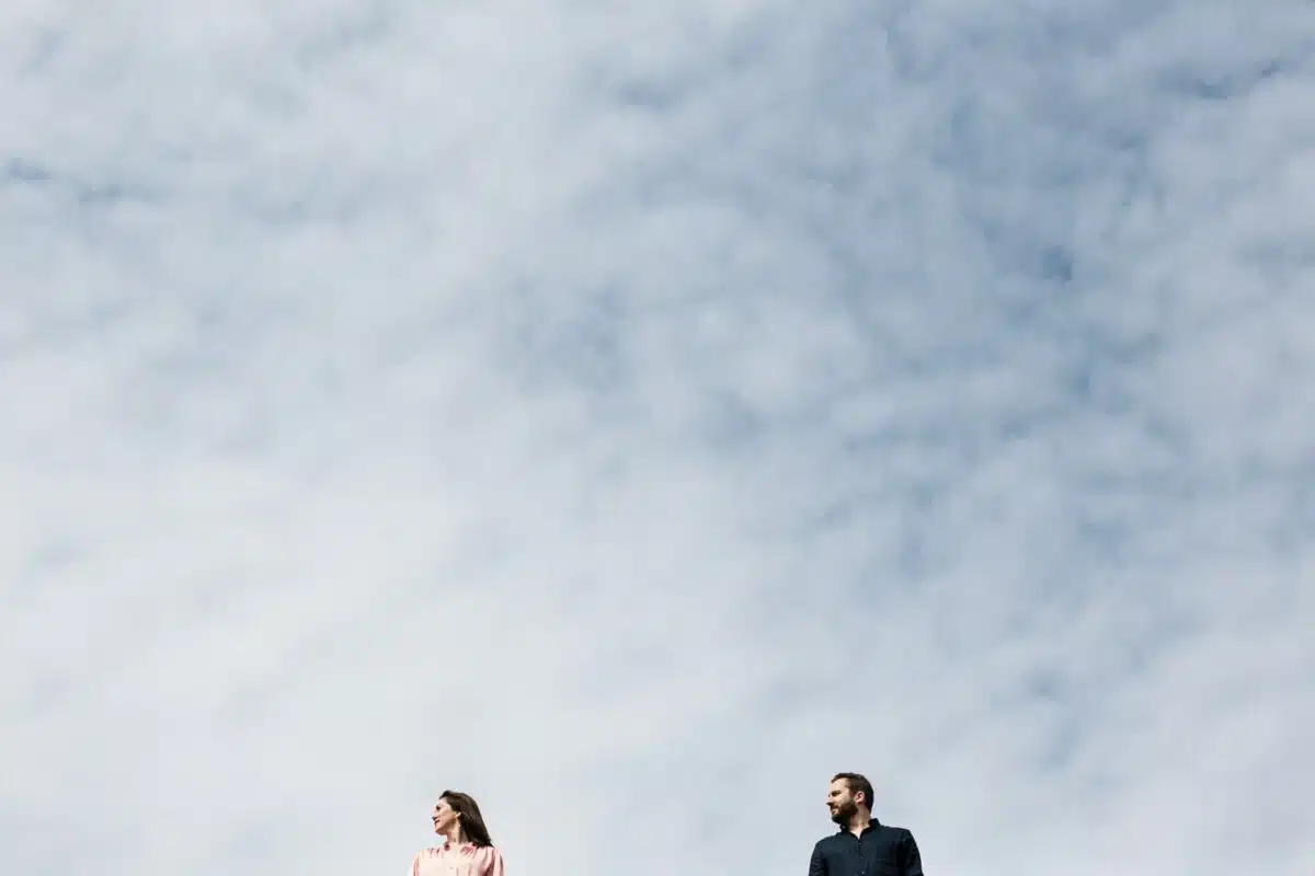 Couple cadré bas sous vaste ciel nuageux, ambiance minimaliste à Nantes.