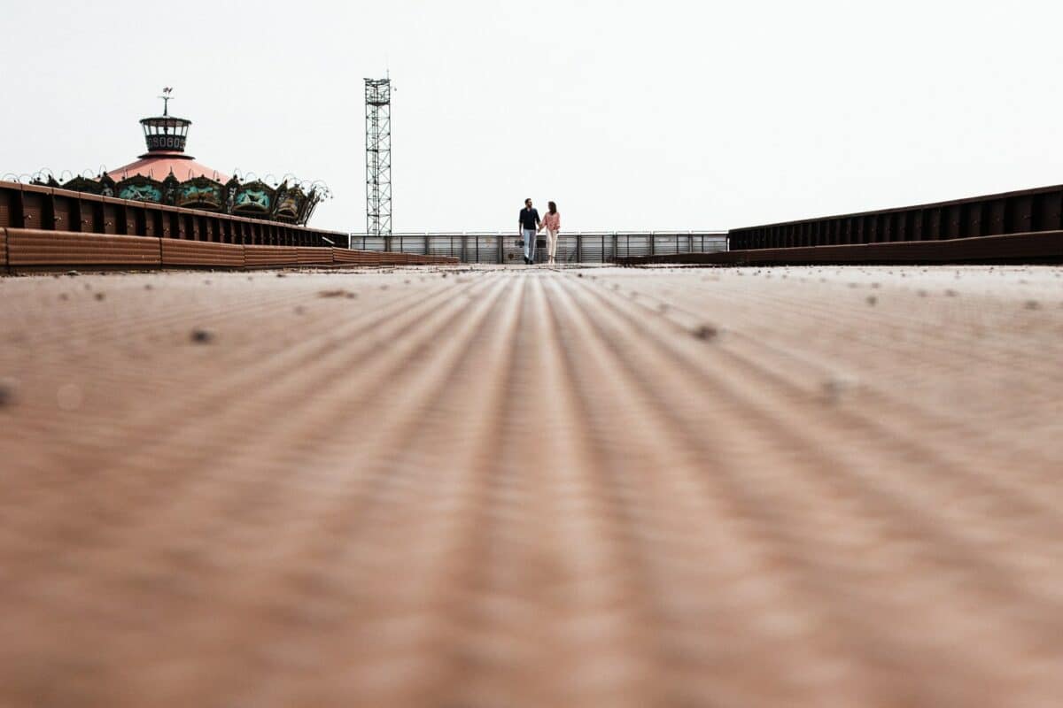 Vue en contre-plongée sur la passerelle rouillée, couple minuscule au centre.
