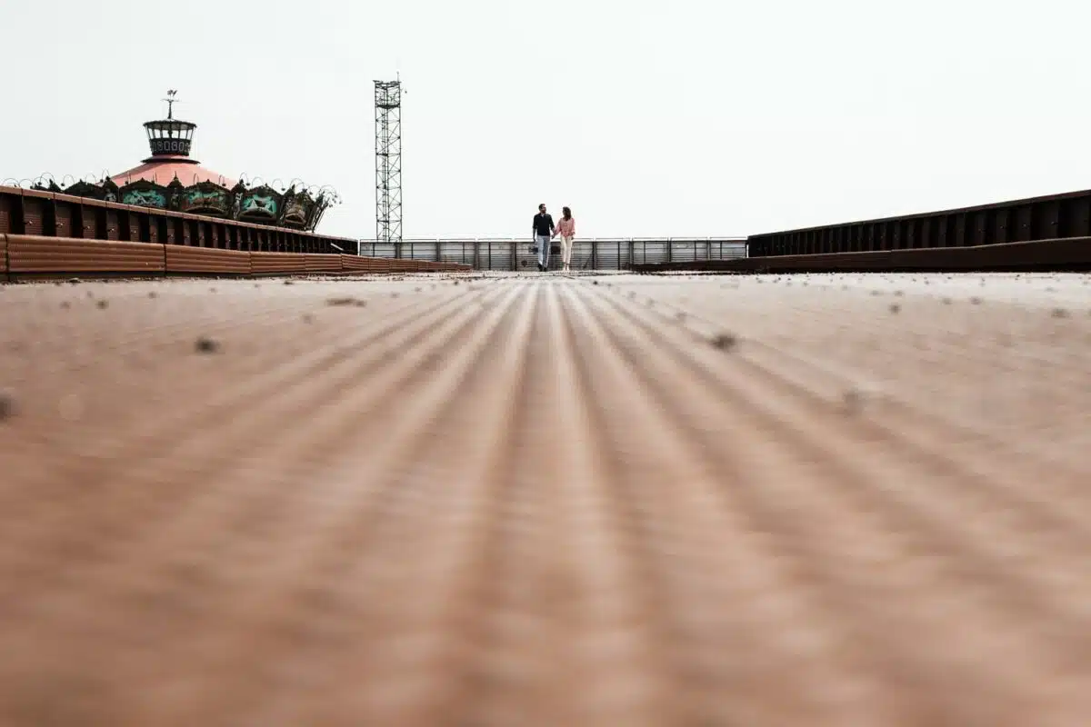 Vue en contre-plongée sur la passerelle rouillée, couple minuscule au centre.