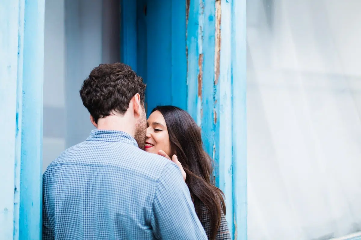 Couple s’embrassant tendrement devant une façade bleue à Trentemoult lors d’une séance engagement à Nantes