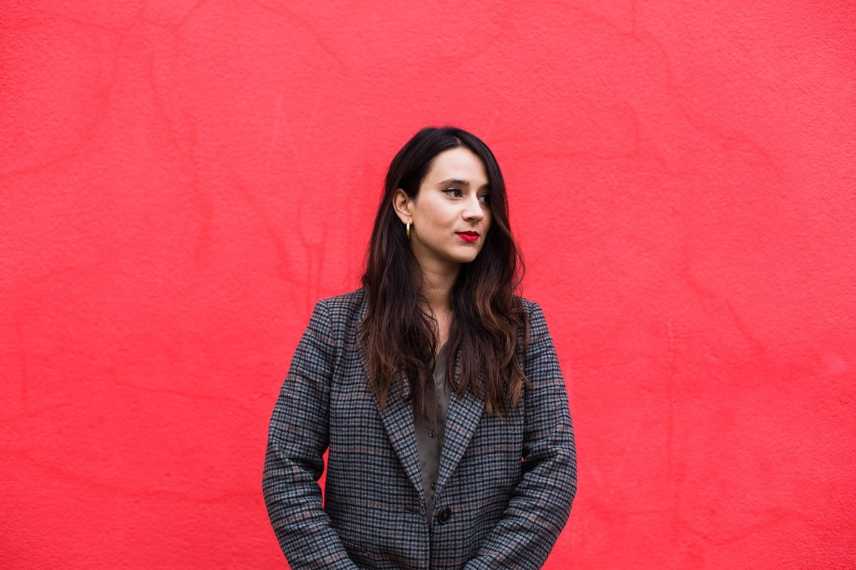 portrait d'une femme brune devant un mur rouge