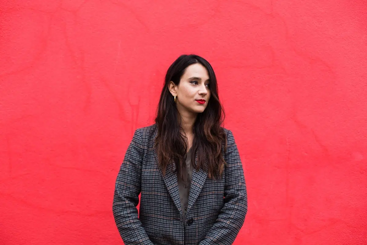 portrait d'une femme brune devant un mur rouge