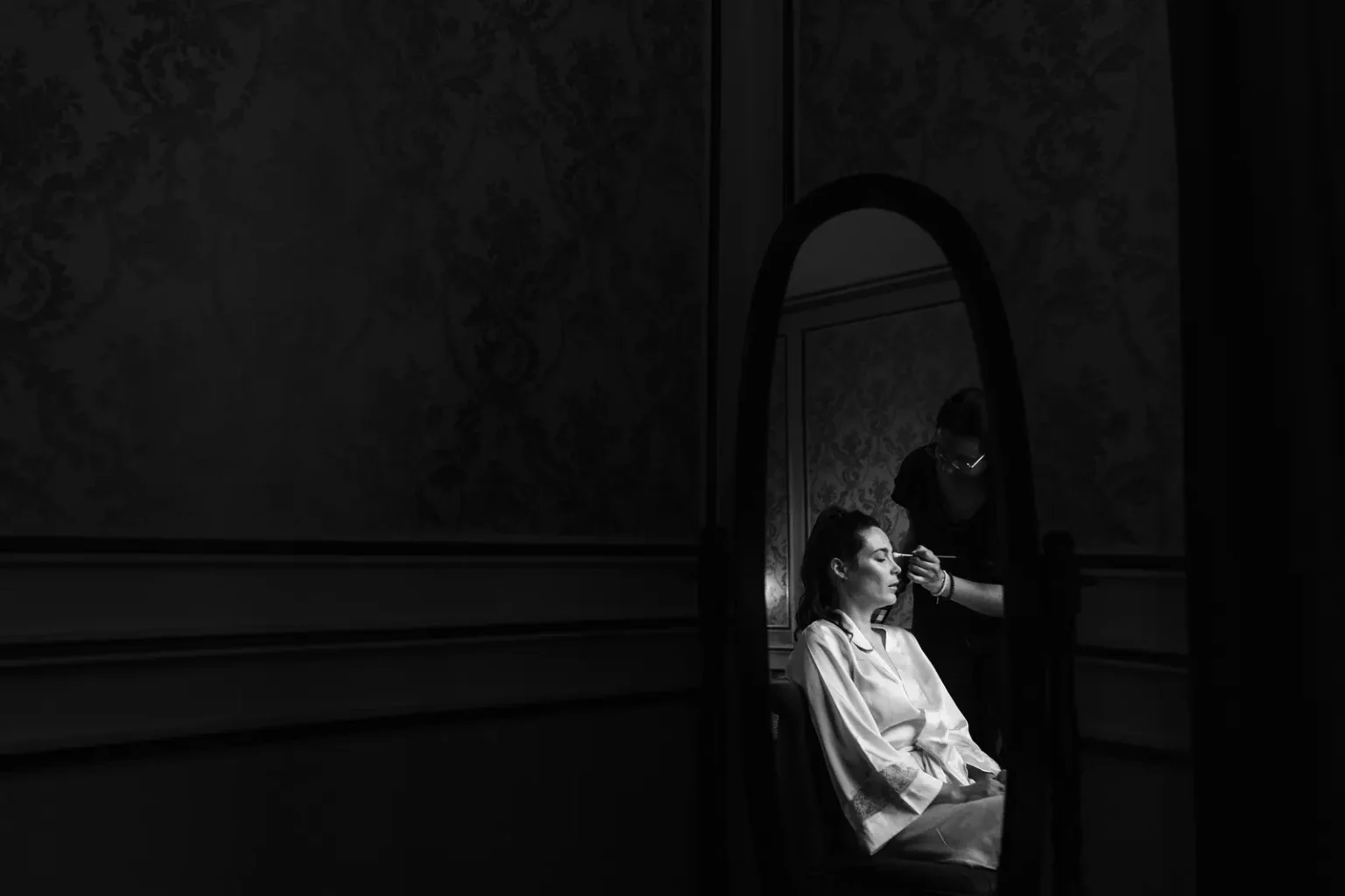 Photographie de mariage en noir et blanc : préparation de la mariée au Château de la Forêt, reflet dans le miroir.