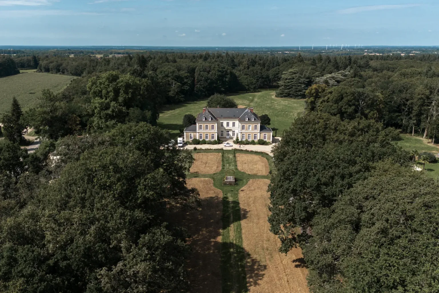 Vue de drone du Château de la Forêt et son domaine boisé, lieu de réception de mariage de prestige.