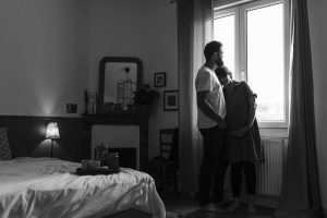 couple devant leur fenetre de chambre lors d'une séance photo romantique