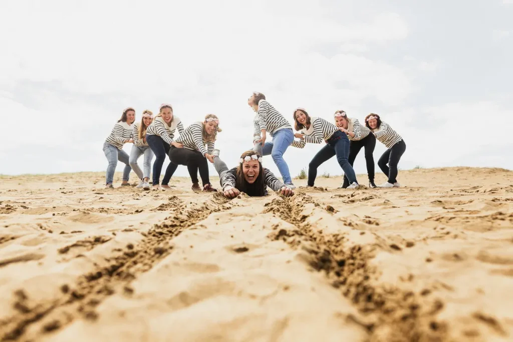 Mise en scène ludique sur une dune : des amies tirent la future mariée allongée dans le sable de St-Brevin.