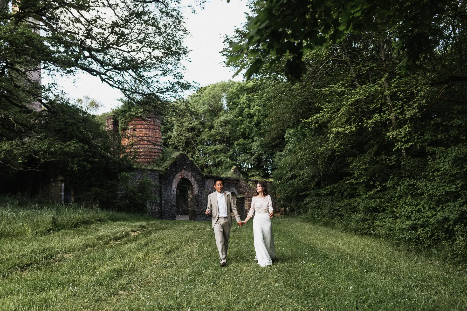 couple marchant main dans la main devant une forge en ruine à Abbaretz au domaine de la Jahotière