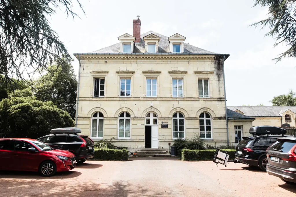 Vue de face du bâtiment principal du Domaine de Roiffé avec voitures stationnées, arrivée des invités pour un mariage.
