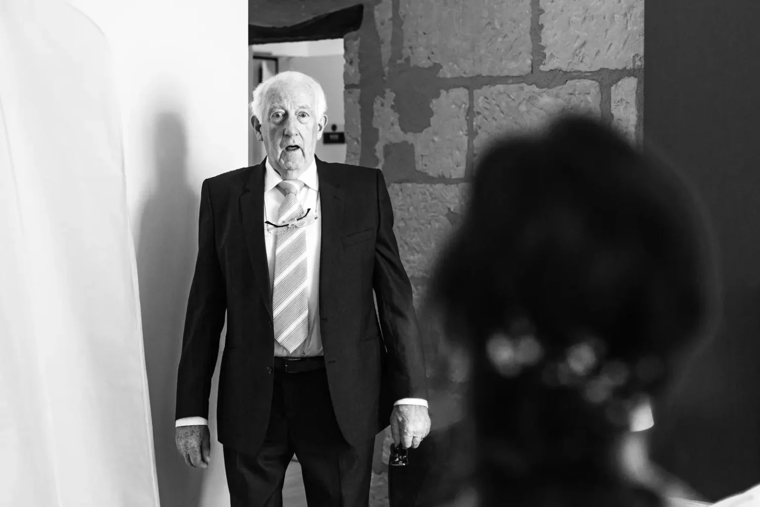 Reportage mariage noir et blanc : expression de surprise et d'émotion d'un proche découvrant la mariée pour la première fois.