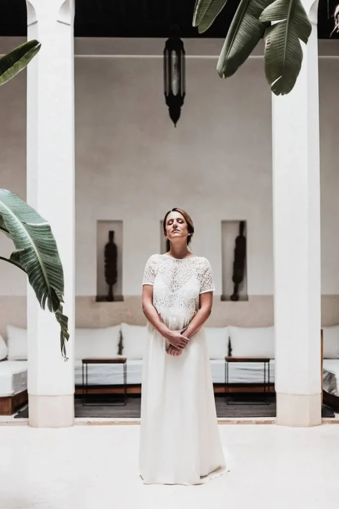 photographe à Nantes. Portrait de mariage stylisé, mariée debout dans une riad ou patio ensoleillé, architecture marocaine.