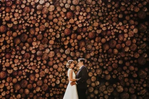 couple de marié pres du domaine de roiffé posant devant des rondins de bois