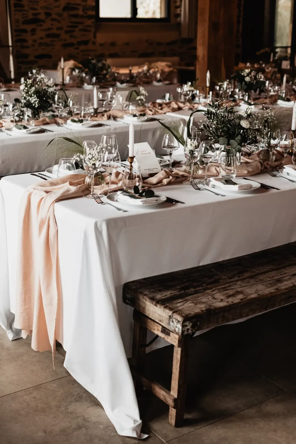 Décoration de table de mariage bohème avec chemin de table en gaze de coton terracotta et compositions florales.