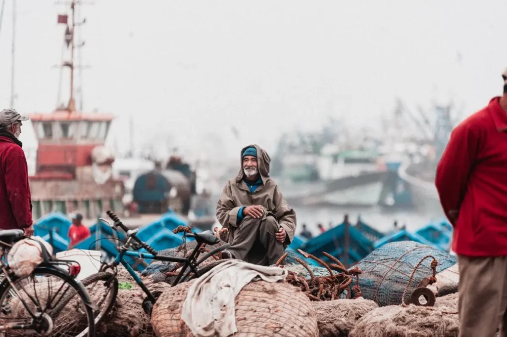 photo de rue de portrait d'un homme assis sur des sacs sur le port d'Essaouira au Maroc