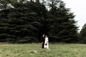 couple de mariés dans le parc du chateau de la foret au cellier devant des sapins