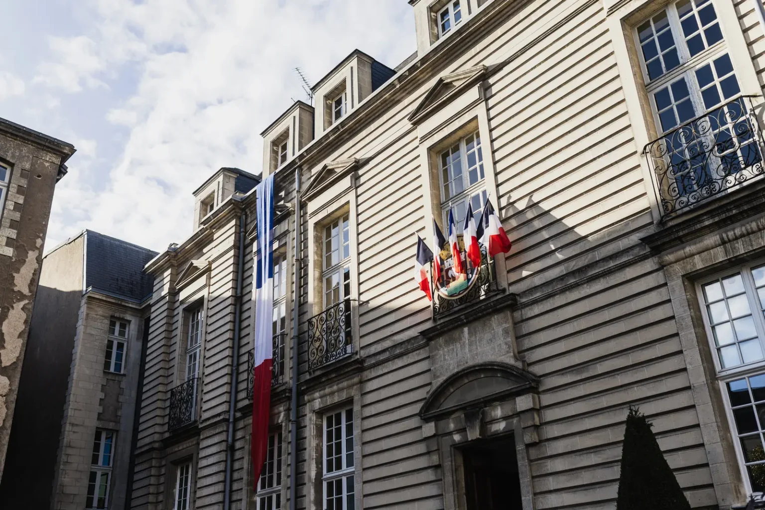 Façade en pierre de la mairie centrale de Nantes ornée de drapeaux français pour un mariage civil.