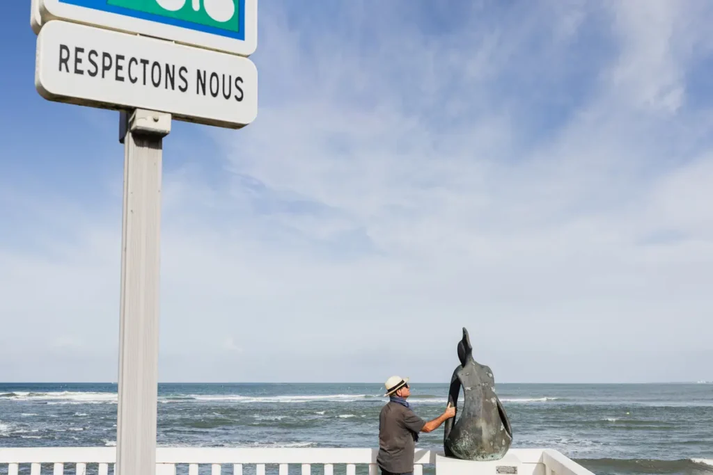 un homme touche une statut sur le front de mer avec un panneau ecrit respectnous a coté