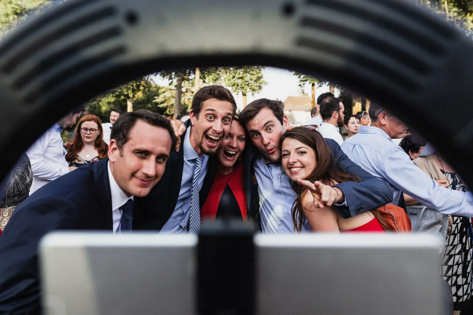 Groupe d'invités joyeux qui se penchent devant un anneau lumineux lors du cocktail de mariage au Domaine des Lys à Ancenis