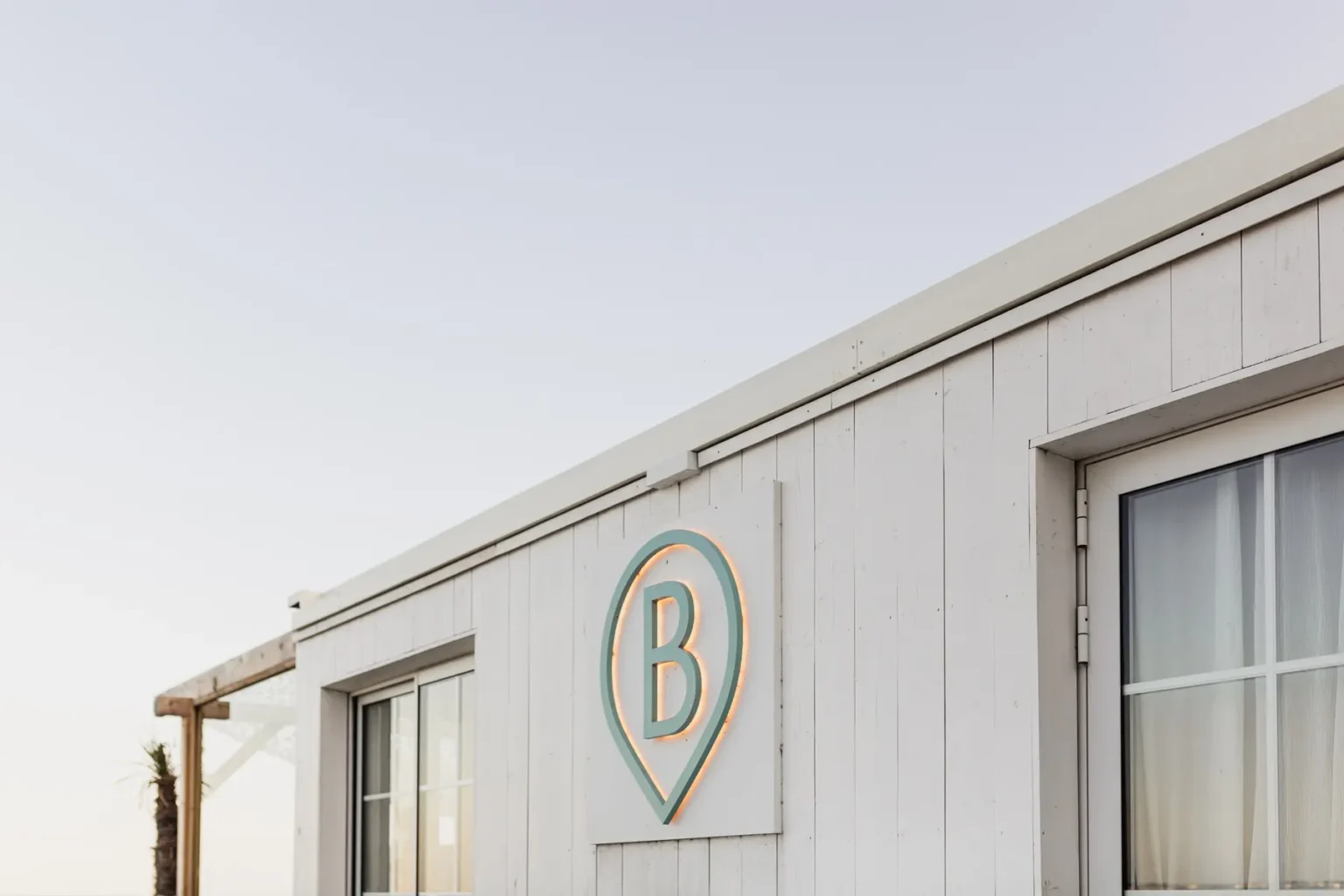 Façade en bois blanc d'un club ou restaurant de plage avec l'enseigne "B" à La Baule.